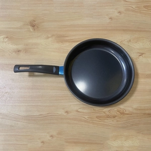 Top view of mini non-stick frying pan with black handle and blue accent on wooden table