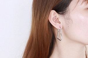 Close-up of a model wearing the minimalist silver heart-shaped stainless steel earring