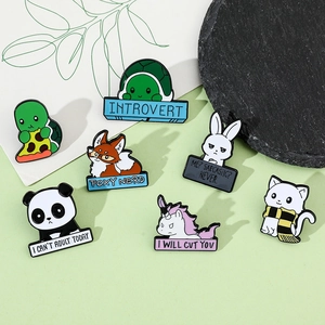 Flat lay of colorful enamel animal brooches with funny slogans on green background