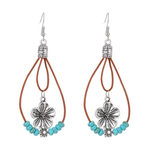 Detail of bohemian earrings with silver flower pendant and turquoise beads on leather cord