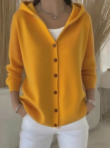 Detail der gelben Strickjacke mit Kapuze, Holzknöpfen und weicher Strickoberfläche