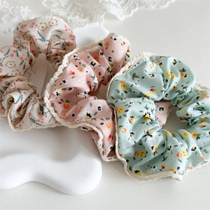 Set of floral fabric scrunchies in beige, pink, and green with white lace trim edges