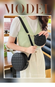 Detail of black quilted round cross-body bag featuring a matching mini coin purse on strap
