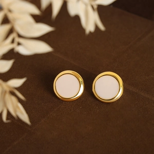 Minimalist geometric round stud earrings with gold metal frame and cream inlay on velvet