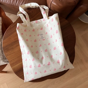 Detailed close-up of cotton floral tote bag with fabric label on a wooden table