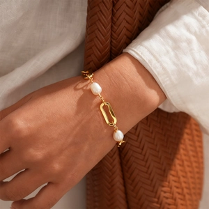 Detail of 18k gold plated oval link bracelet with freshwater pearls on woman wrist