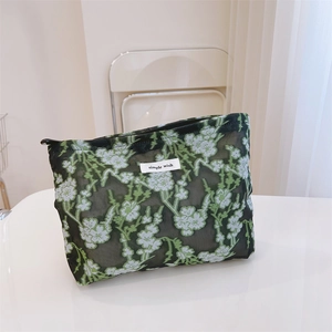 Detailed close-up of floral embroidery on black mesh makeup bag with simple wish label