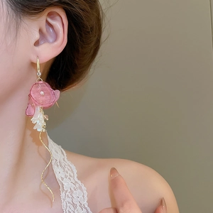 Detail of pink fabric flower earrings with zircon pearls and long gold tassel chains