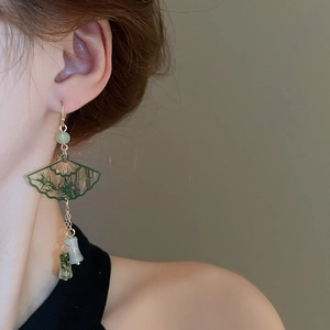 Close-up of Neo-Chinese earrings with green fan pendant and bamboo motif on a model