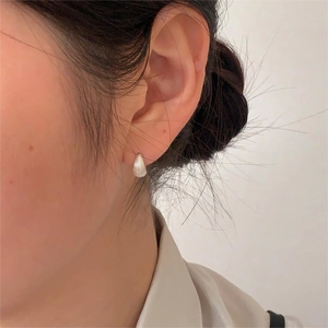 Detailed close-up of shell-shaped 925 sterling silver stud earring on model ear