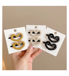 Detailed view of heart-shaped hair clips in yellow, beige, and black on display cards