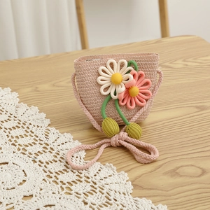 Close-up of pink straw woven crossbody bag with large floral accents and green pompoms