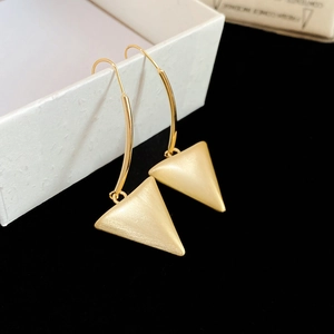 Detail of 18k gold-finished triangle drop earrings with brushed metal texture on white box