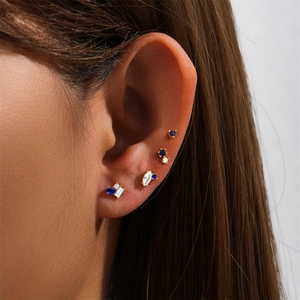 Macro shot of 925 silver gold-plated stud earring set with blue and white stones