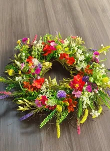 Detail of colorful artificial wildflower wreath on rustic wooden background