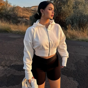 Detailed close-up of a white zip-up hoodie and black biker shorts on a model at sunset