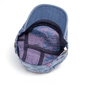 Dettaglio del berretto in denim lavato con fodera a stampa astratta e fibbia in metallo