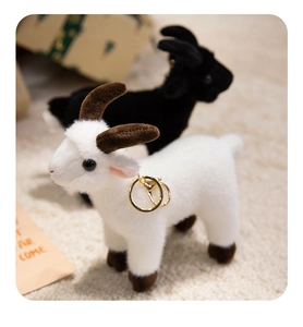 Close-up of cute plush goat charms in black and white with golden keychains