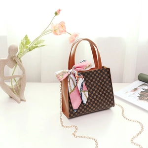 Detailed view of dark brown tote bag with vintage pattern, golden chain and pink silk scarf