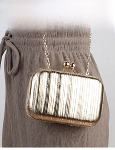 Detail of gold pleated evening clutch with vertical texture and metal chain strap