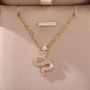 Detailed macro view of the gold snake pendant set with white zircons and green gem eyes