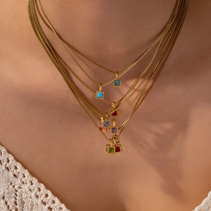 Layered gold box chain necklace with multi-color square zirconia stones on a model