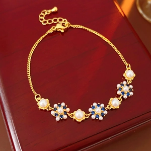 Macro detail of vintage floral pearl bracelet with gold chain and zircon flower petals