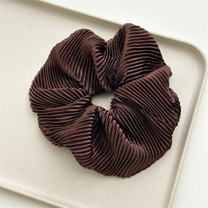Detailed view of dark brown pleated satin scrunchie with a silky cream luster finish