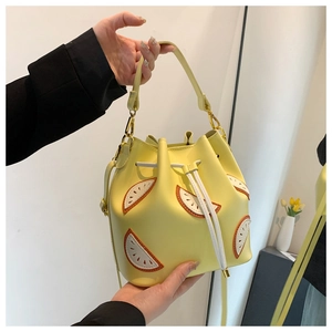Handheld view of a yellow lemon bucket bag with fruit slice appliqué and drawstring closure