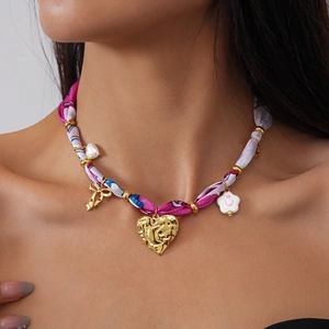Detail of pink floral fabric necklace with heart and smile flower charms on a model