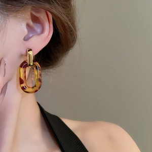 Detail view of leopard print resin chain earrings with gold metal links on a model