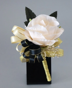 Détail de la boutonnière rose en soie blanche avec rubans champagne et noir dorés