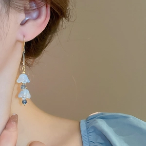 Détail de boucles d'oreilles muguet bleu clair avec crochet doré sur modèle