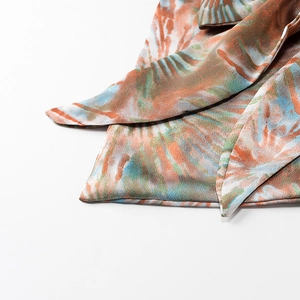Detailed close-up of vibrant tie-dye pattern on smooth satin fabric for summer tops