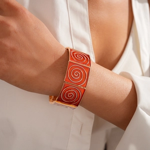 Detail of wide gold-edged bangle with orange enamel and spiral scroll patterns