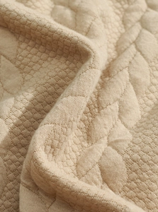 Close-up of khaki jacquard knit fabric with geometric quilted pattern and soft texture