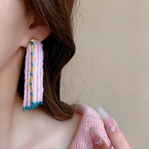 Détail de boucles d'oreilles élégantes avec pompons de perles roses et métal doré