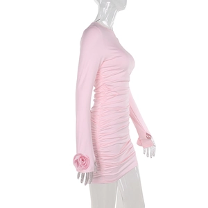 Detail of pink slim-fit dress featuring side ruching and 3D rose applique on the cuff