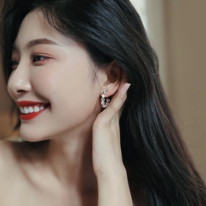 Close-up of elegant C-shaped gold-plated earrings with cat-eye stones on a model