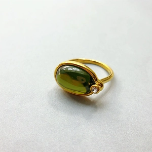 Nahaufnahme eines 18K vergoldeten Rings mit großem ovalem grünem Edelstein und Zirkon