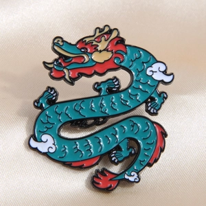 Detailed view of enamel dragon pin with green and gold finish on beige satin fabric