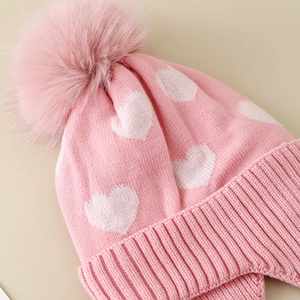 Pink winter knit hat for girls with white heart jacquard and a fluffy faux fur pompom