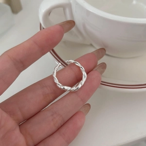 Adjustable 925 sterling silver twisted rope ring shown on a hand with a white ceramic cup