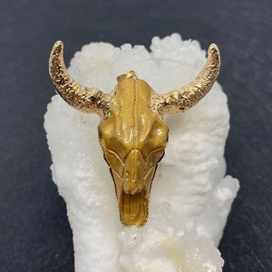 Macro shot of golden bull skull pendant on white crystal texture with intricate details