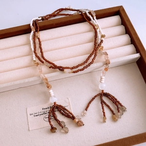 Detail of ethnic glass beaded necklace featuring bohemian tassels and irregular gemstones