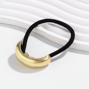 Detail shot of a minimalist gold crescent metal hair tie with a black elastic band