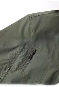 Detail der militärgrünen Jacke mit verstärkter Schulter und Reißverschlusstasche