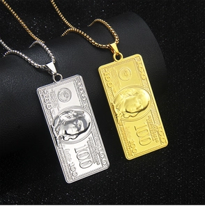 Detailed close-up of gold and silver dollar sign necklaces on a sleek black pedestal