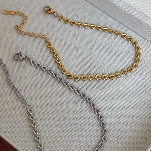 Detailed view of woven heart-shaped chain bracelets in polished gold and silver finishes
