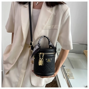Detail of black embossed cylindrical bag with silk scarf handle and gold lock charms